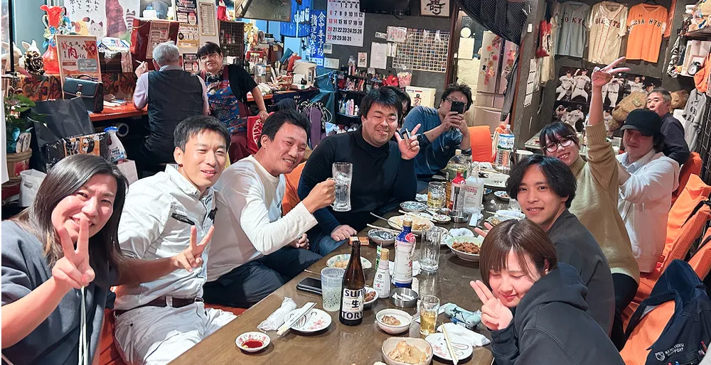 飲み会のイメージ写真。多数の社員がテーブルを囲んで、飲み会を楽しんでいる