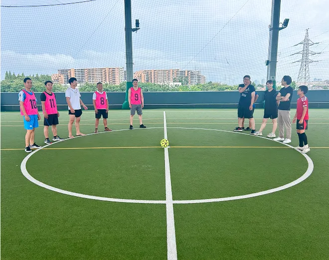 フットサルの写真。社員やその家族が5人チームに分かれて、センターサークルを囲んで写っている。