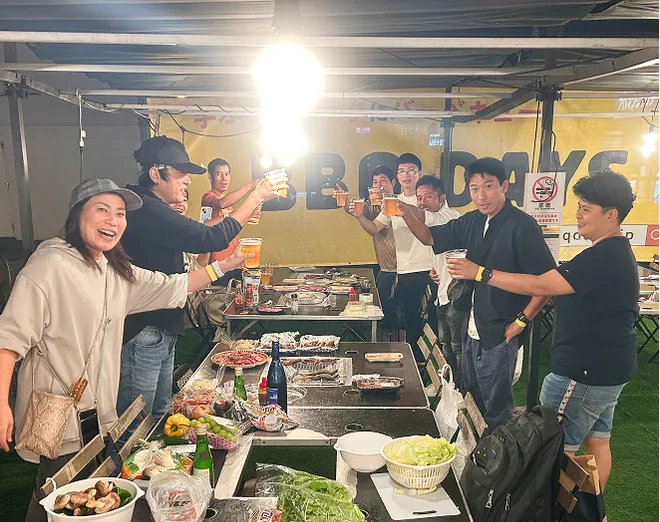 BBQの写真。社員がビールを持って乾杯している。