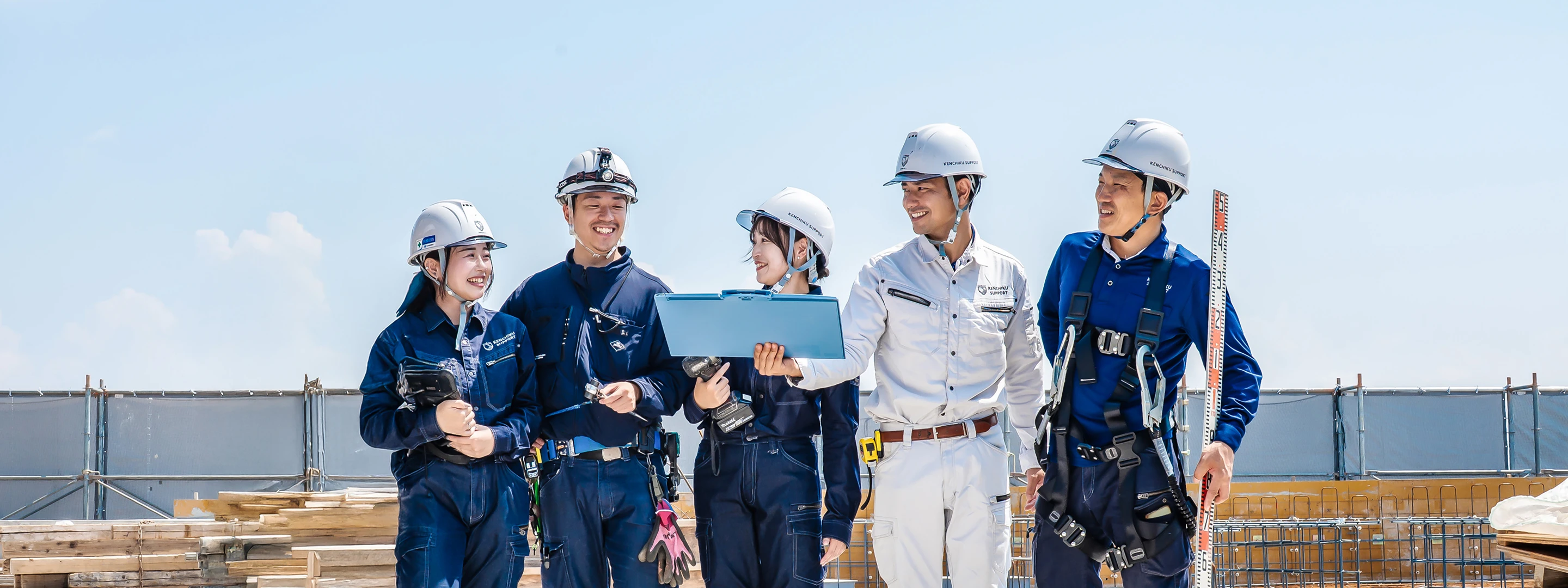作業員（左から女性1人、男性1人、女性1人、男性2人）が話し合っている様子。