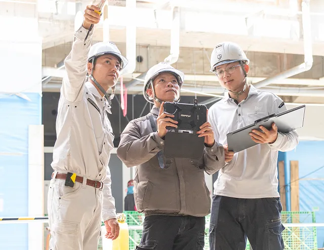 建築施工管理支援のイメージ写真。工事現場を前に、作業員が確認をしている様子が写っている。