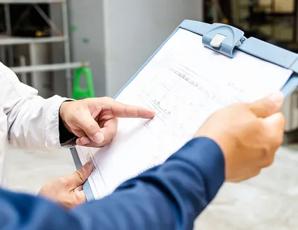 工程管理のイメージ写真。作業員が図面を見ながら話し合っている様子の手元を写している。