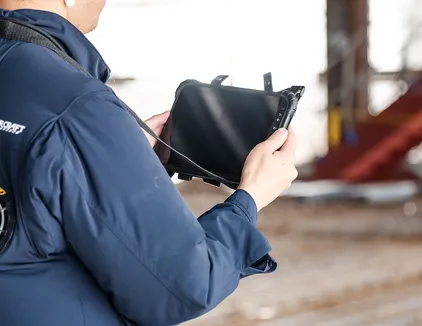 工事写真撮影のイメージ写真。作業員が端末で記録を確認している。