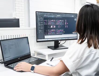図面作成（CAD）のイメージ写真。社員がパソコンとモニターの画面を見ながら作業をしている。